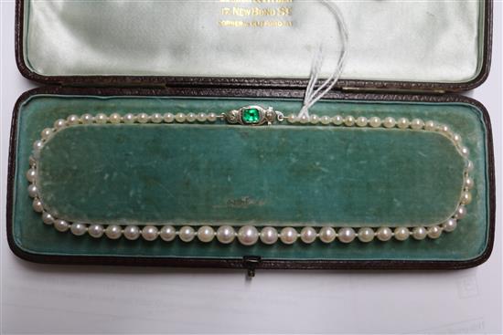 A single strand graduated cultured pearl necklace with an emerald and diamond set white metal clasp, approx. 35cm.